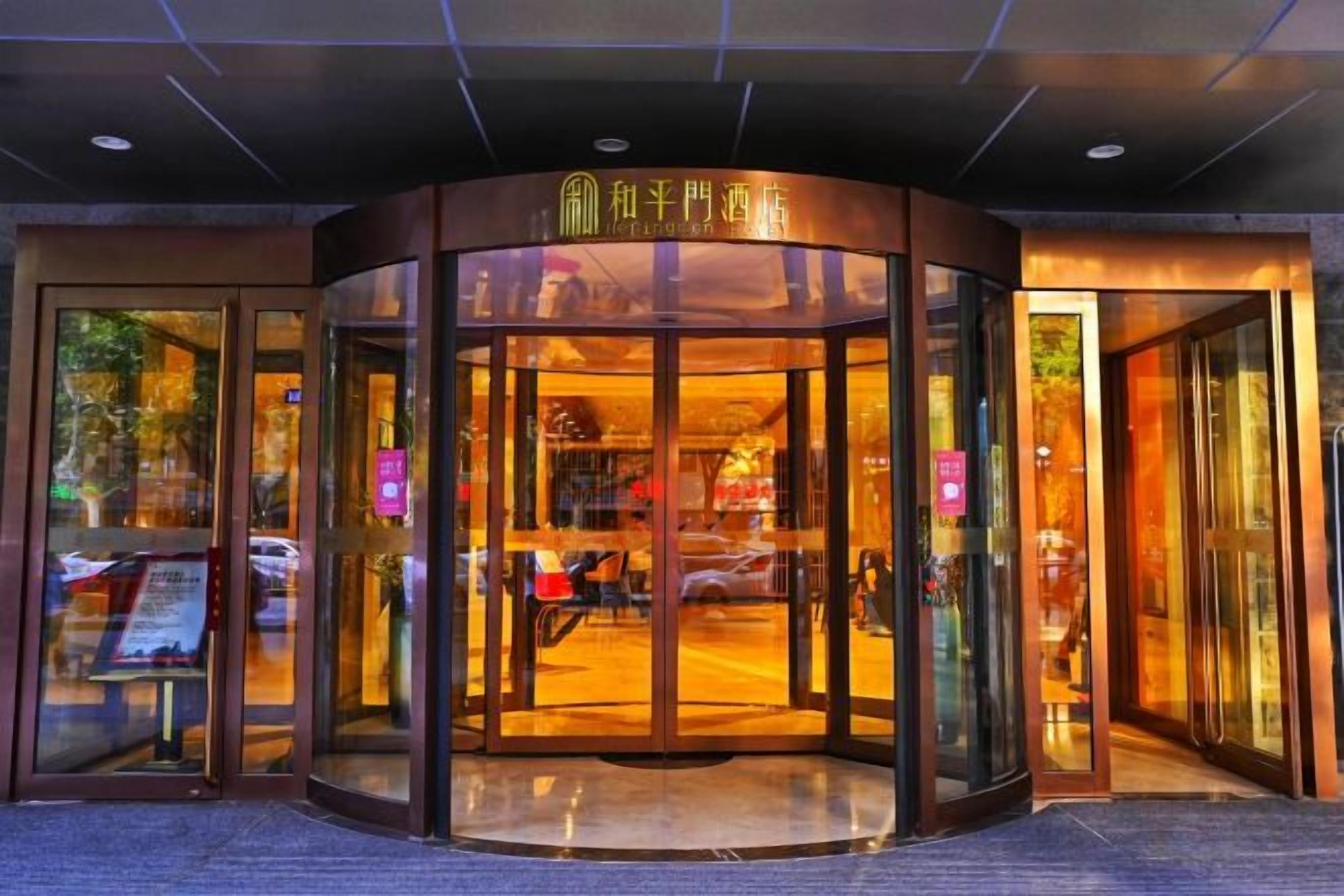 Fachada de un hotel con puerta giratoria, puertas de cristal y un cartel sobre la entrada.