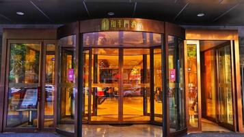 Fachada de un hotel con puerta giratoria, puertas de cristal y un cartel sobre la entrada.