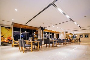 A modern restaurant with a long counter and multiple tables, large windows, and a high ceiling. - Xi'an Peace Arch Hotel (Xi'an)