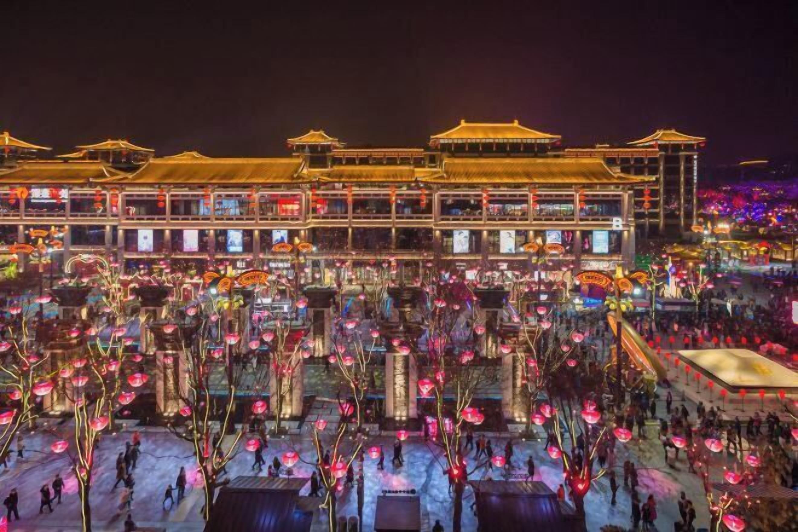 A traditional building with multiple levels and a courtyard filled with people and lanterns.