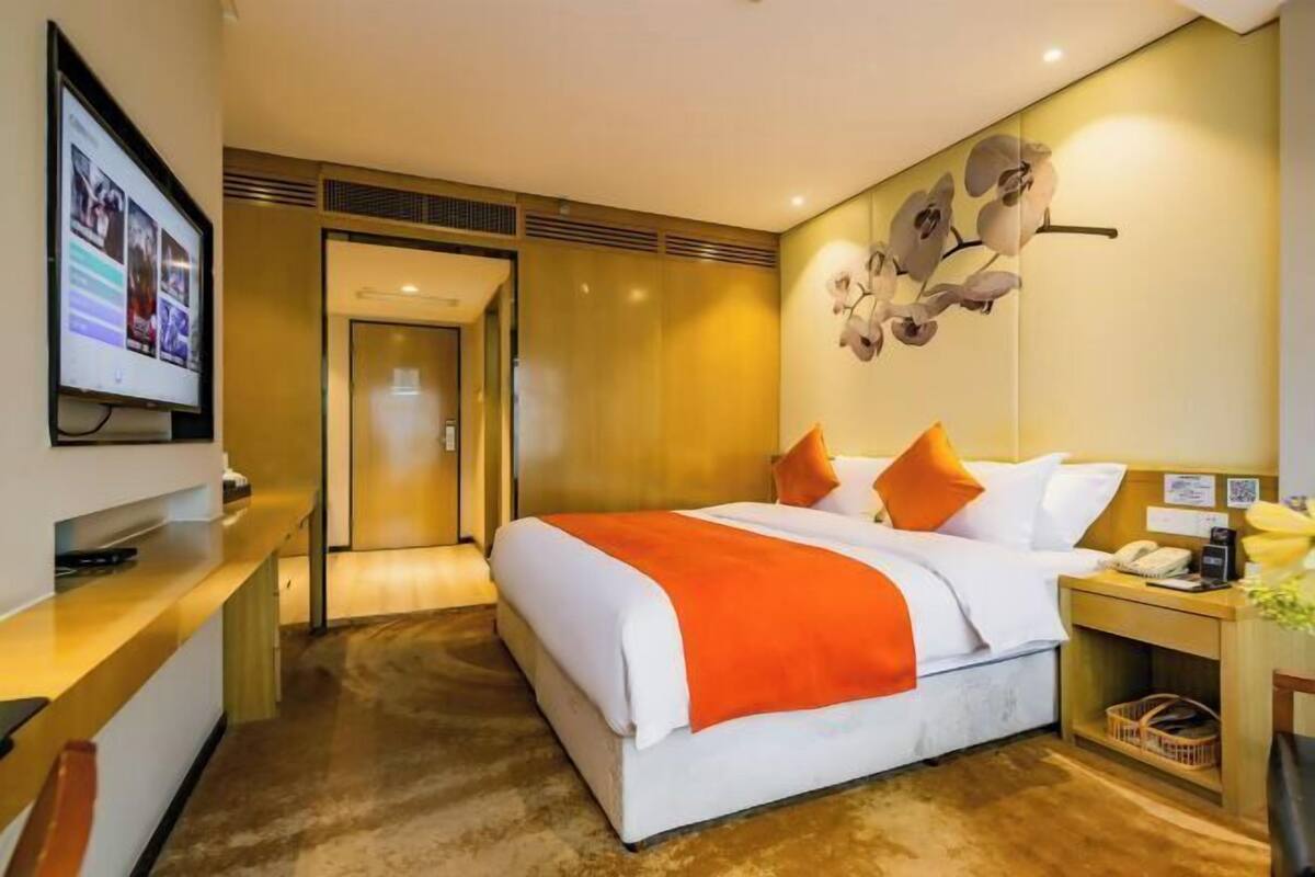 Une chambre d’hôtel équipée d’un lit, d’un bureau, d’une télévision et d’une œuvre d’art accrochée au mur.