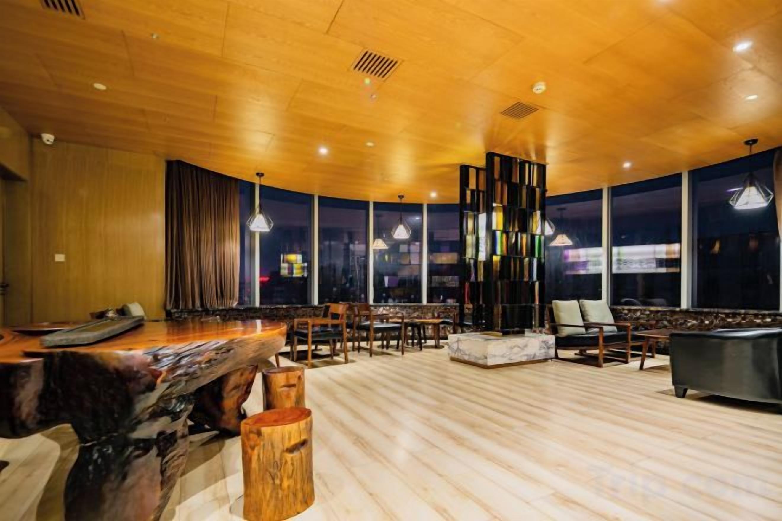 Una habitación amplia con techo de madera, una mesa de billar y una zona de estar con sillas y sofá.