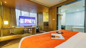 A hotel room with a bed, a desk, a television, and a view of the outside.
