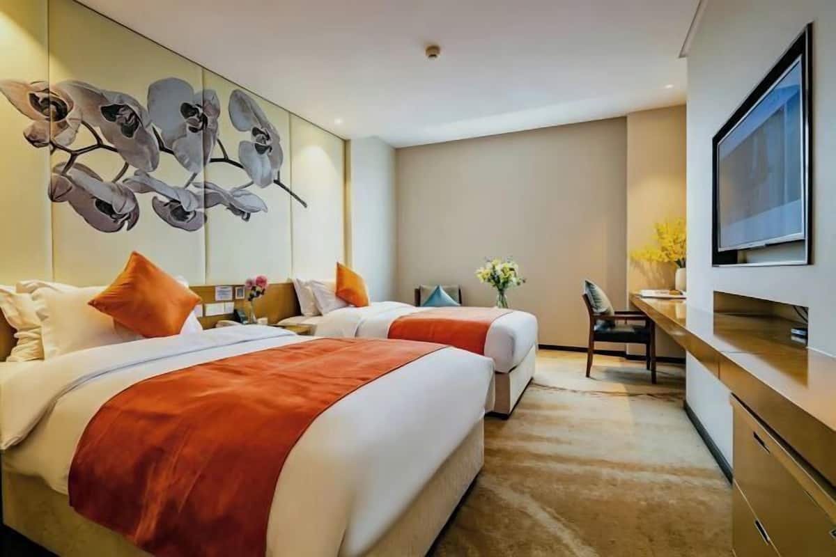 Une chambre d’hôtel avec deux lits, un bureau, une chaise, une télévision et une œuvre d’art accrochée au mur.