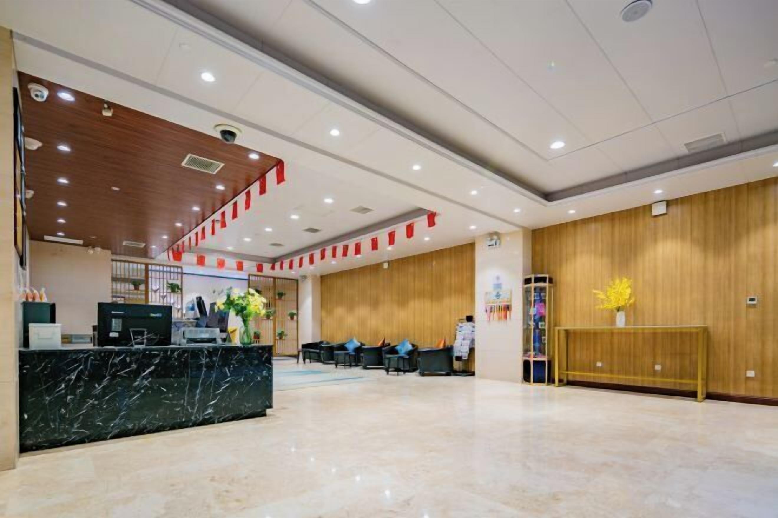 Zona de recepción de hotel con mostrador de mármol, área de descanso y paneles de madera en las paredes.