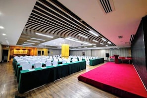 A conference room with rows of white chairs, a stage with a red carpet, and a high ceiling with linear lighting fixtures. - Xi'an Peace Arch Hotel (Xi'an)