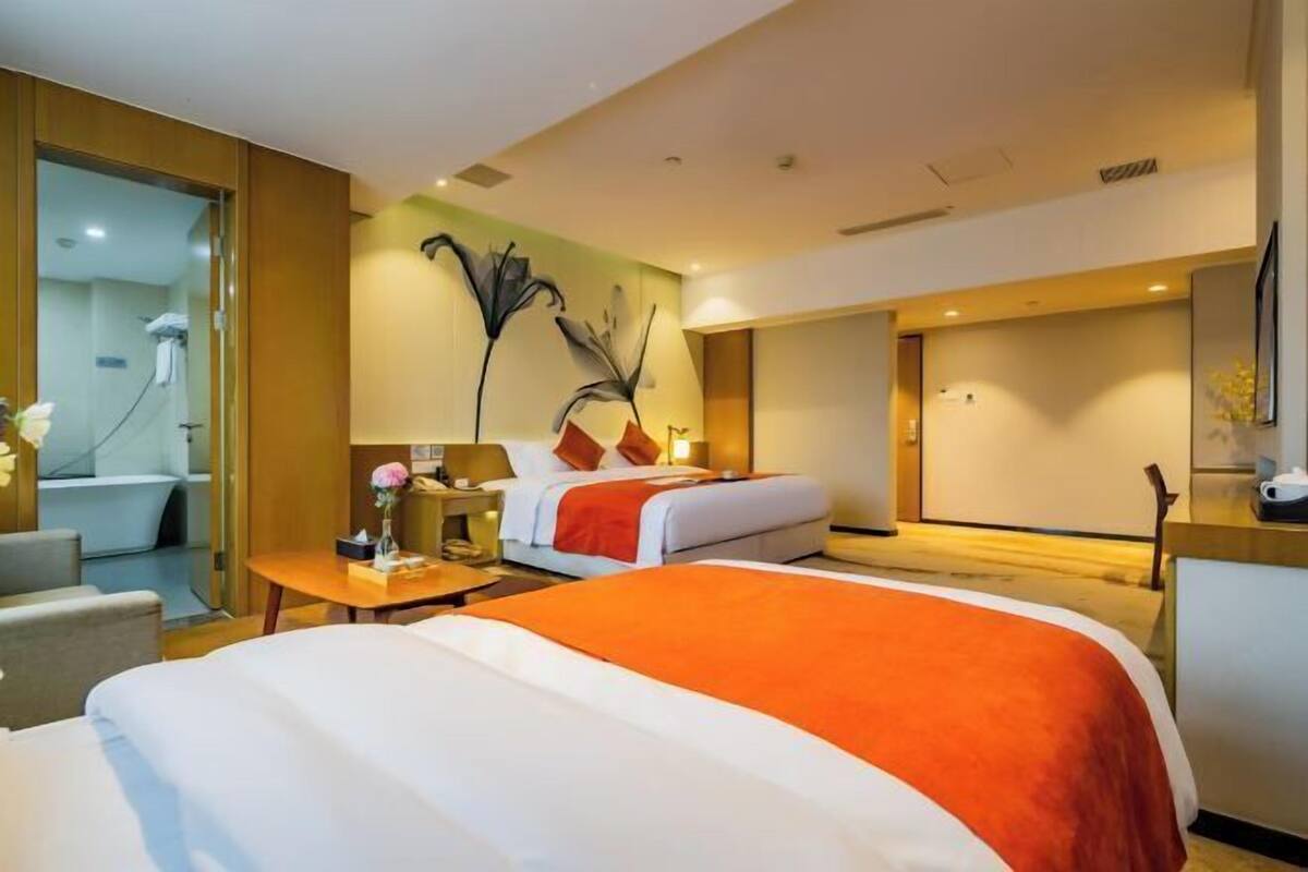 Une chambre d’hôtel comprenant un lit, un bureau, une chaise, une salle de bain et une grande œuvre d’art murale.