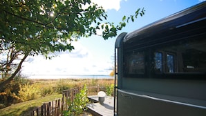 A train station platform with a wooden fence, a pathway, and a view of the sea in the background. - Dreamer Luxus-Caravan am Achterwasser, Lütow (Lütow)