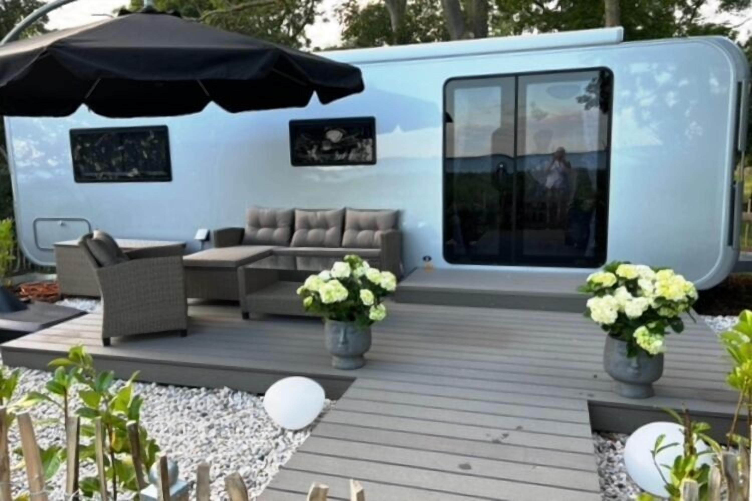 Ein Wohnmobil mit einer Terrassenfläche, komplett mit Gartenmöbeln und Blumentöpfen.