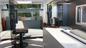 A compact living space with a sofa, a small table, a kettle, and a window with a view of greenery. - Dreamer Luxus-Caravan am Achterwasser, Lütow (Lütow)