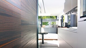 A modern kitchen with a glass partition, a dining area with a table and chairs, and a view of the outdoors. - Dreamer Luxus-Caravan am Achterwasser, Lütow (Lütow)