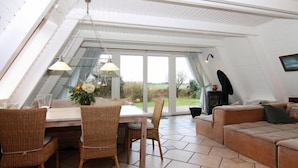 Ein Essbereich mit Tisch, Stühlen, einer Couch und Blick ins Freie.