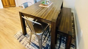 A dining area with a wooden table, metal chairs, a patterned rug, a hanging light fixture, and a framed picture on the wall. - Cascade Basecamp: close to fun! (Cascade)