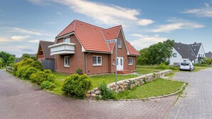 A residential house with a red-tiled roof, a brick exterior, and a paved driveway. - Wohnung in St.Peter Ording (St.Peter Ording)