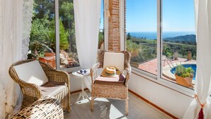 Un balcon agrémenté de meubles en osier, d’une petite table et offrant une vue sur une piscine et un paysage.