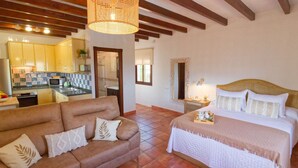 Une chambre avec un lit, un canapé et une cuisine en arrière-plan.