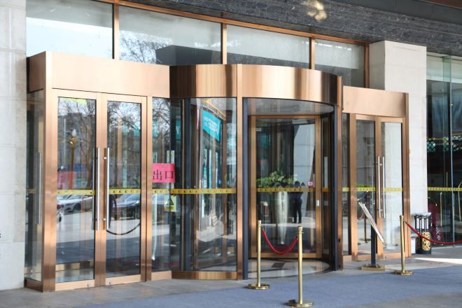A revolving door entrance with glass panels and a red rope barrier.