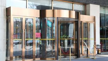 A revolving door entrance with glass panels and a red rope barrier.