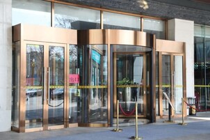 Entrada con puerta giratoria, paneles de vidrio y una barrera de cuerda roja.