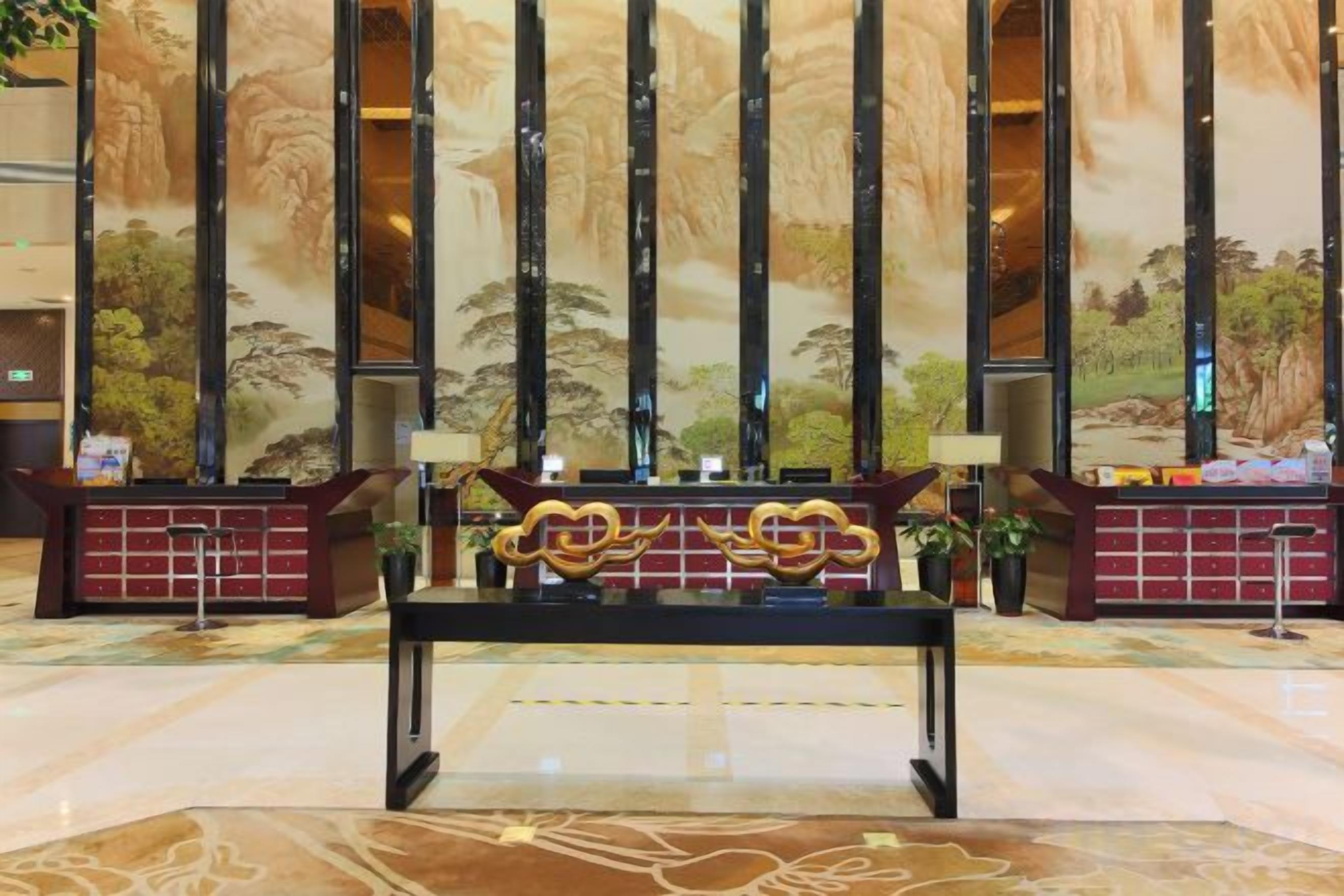 A reception desk with a modern design, flanked by vertical columns and a mural depicting a natural landscape.