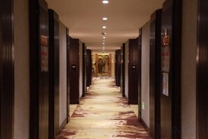 A hotel corridor with doors on both sides, a patterned carpet, and a ceiling with recessed lighting. - Chenguang Hotel (Xingtai)