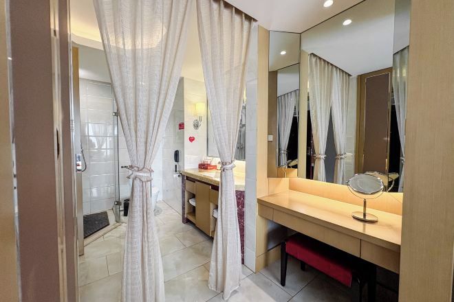 A bathroom with a shower, a mirror, and a vanity with a sink and a towel rack.