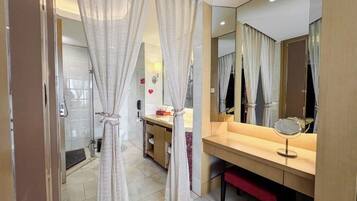 A bathroom with a shower, a mirror, and a vanity with a sink and a towel rack.