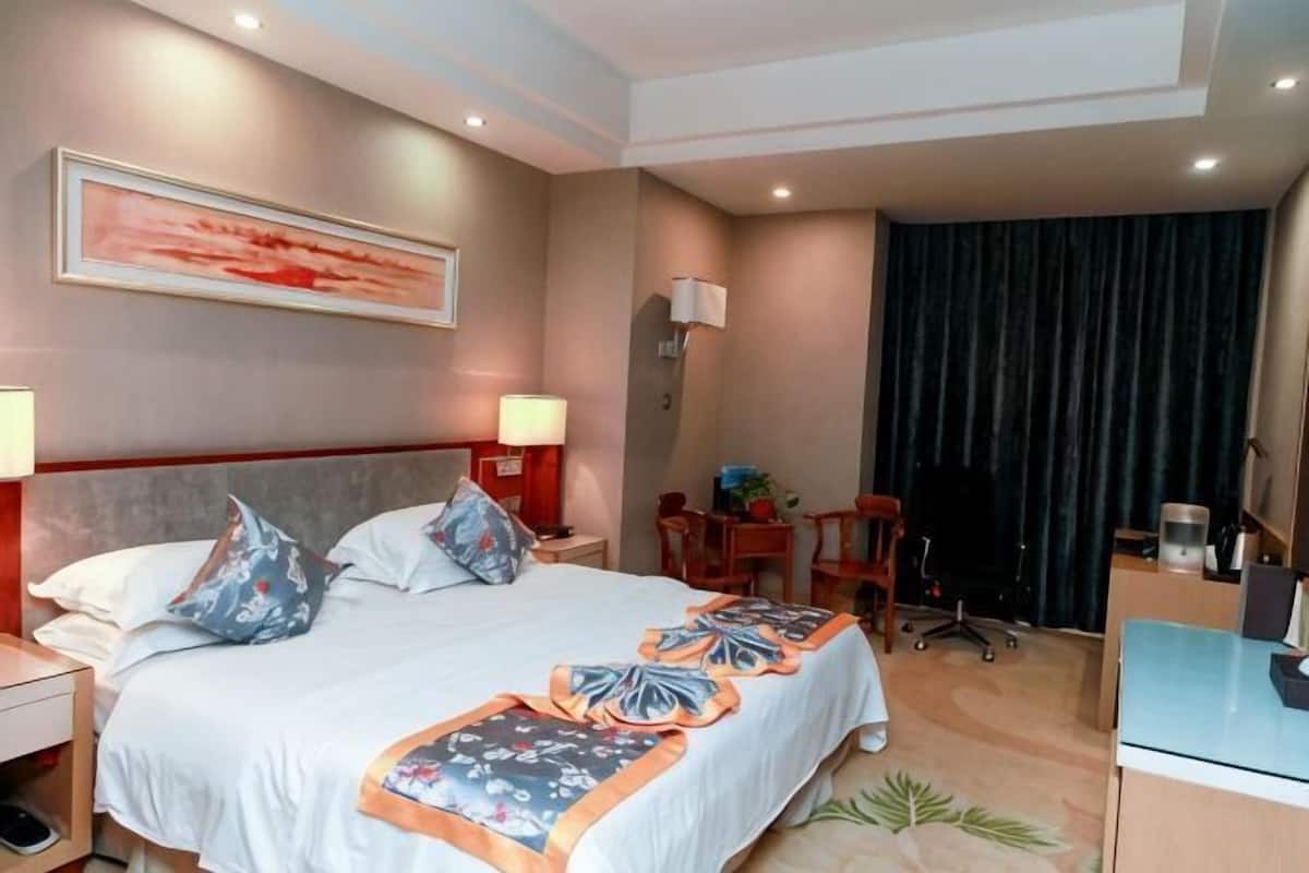 Una habitación de hotel con cama, mesitas de noche, escritorio y una silla.