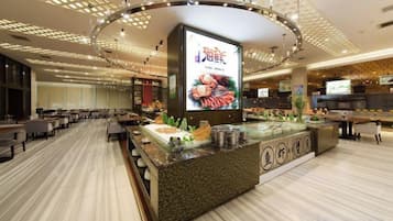 A hotel lobby with a central reception desk, seating area, and a large digital screen.