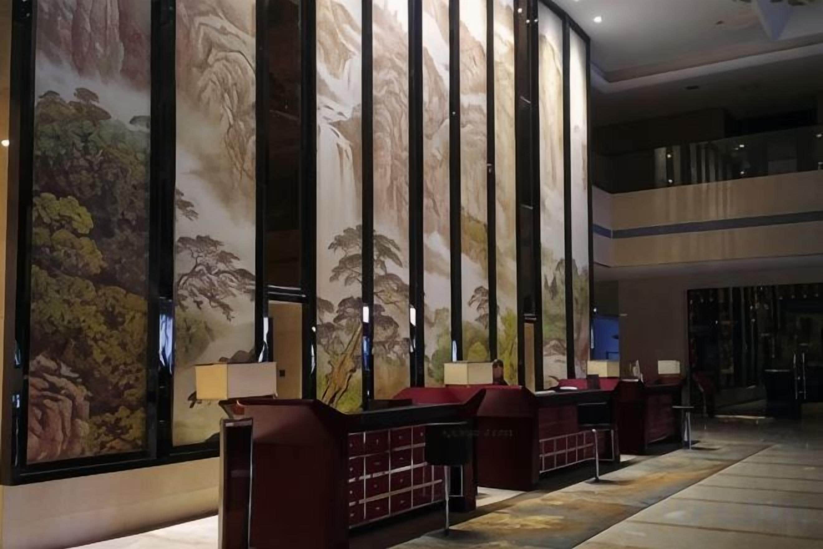A lobby with a large mural, seating areas, and a staircase.