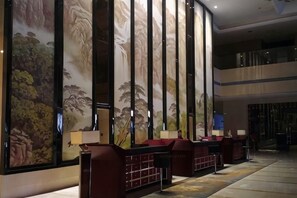 Un vestíbulo con un gran mural, zonas de estar y una escalera.