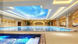 An indoor swimming pool with a skylight ceiling, a separate smaller pool, and lounge chairs along the sides. - Chenguang Hotel (Xingtai)