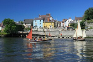 Two sailboats on a calm river with a stone bridge and colorful buildings in the background. - The Old Cottage, Aberporth (Glanrhyd)