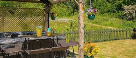 An outdoor patio with a table, chairs, and hanging planters.
