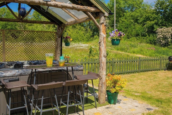 An outdoor patio with a table, chairs, and hanging planters.