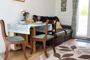 A dining area with a table set for four, a sofa, and a window with curtains.