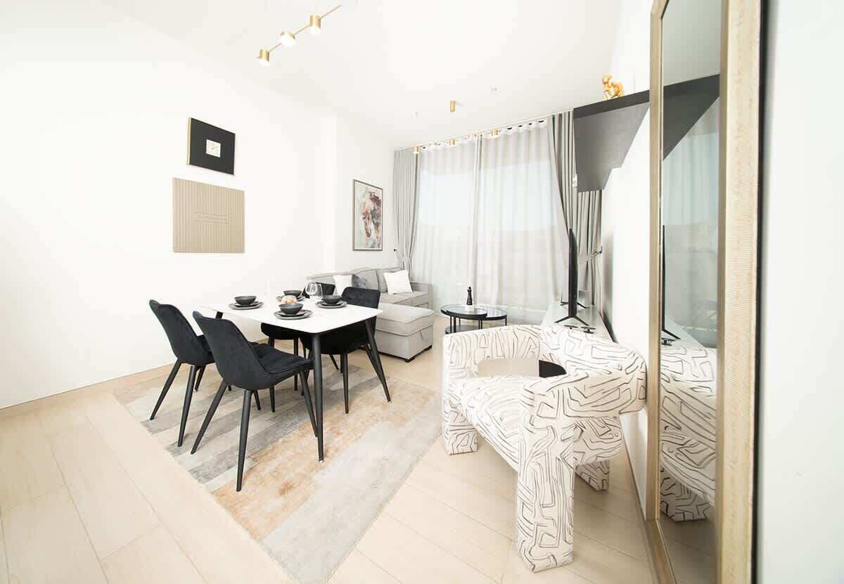 A modern living room with a dining area, a sofa, a coffee table, and a large mirror.