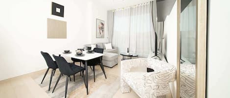 A modern living room with a dining area, a sofa, a coffee table, and a large mirror.