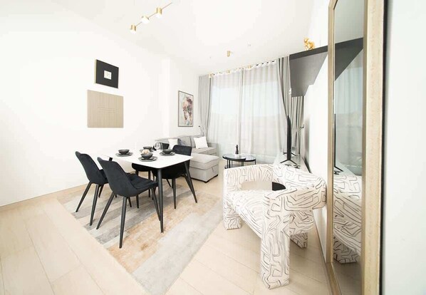 A modern living room with a dining area, a sofa, a coffee table, and a large mirror.