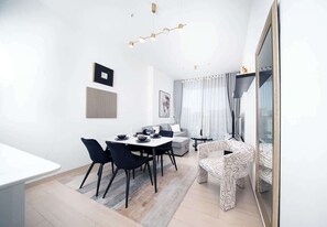 A modern living room with a dining area, a sofa, and a patterned armchair.