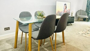 Un espace repas moderne avec une table en verre et des chaises à revêtement gris.
