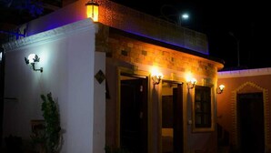 A building with a white facade, a brick upper section, and multiple doors. - Sofia Guest House (Luxor)