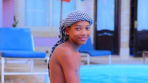 A person sitting by a pool with a blue and red umbrella in the background. - Sofia Guest House (Luxor)