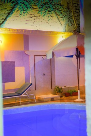 An indoor swimming pool with a lounge chair, a door, and potted plants. - Sofia Guest House (Luxor)