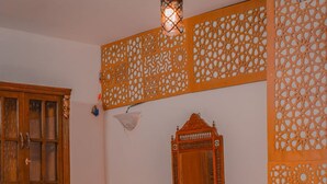A room with a wooden cabinet, a table with chairs, a bed, and decorative wall panels. - Sofia Guest House (Luxor)