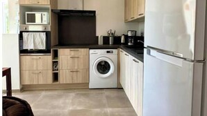 Une cuisine compacte équipée d’un four à micro-ondes, d’un four traditionnel, d’un lave-linge et d’un réfrigérateur.