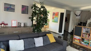 Un salon moderne avec un canapé gris, une bibliothèque et une grande plante.