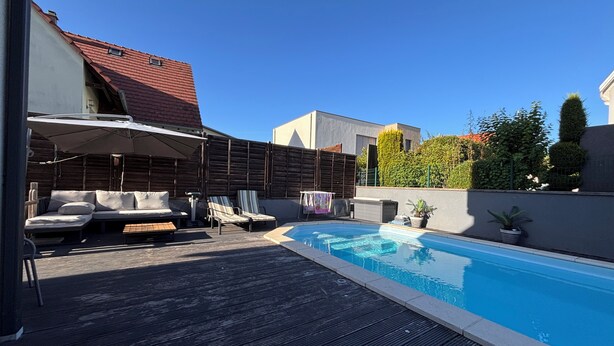 Une piscine avec des chaises longues et un espace de repos abrité.