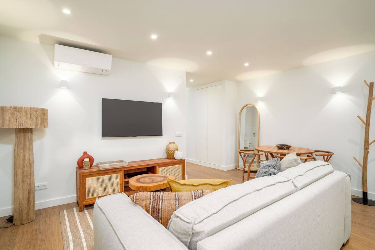 A modern living room with a sofa, a coffee table, a TV, and a dining area.