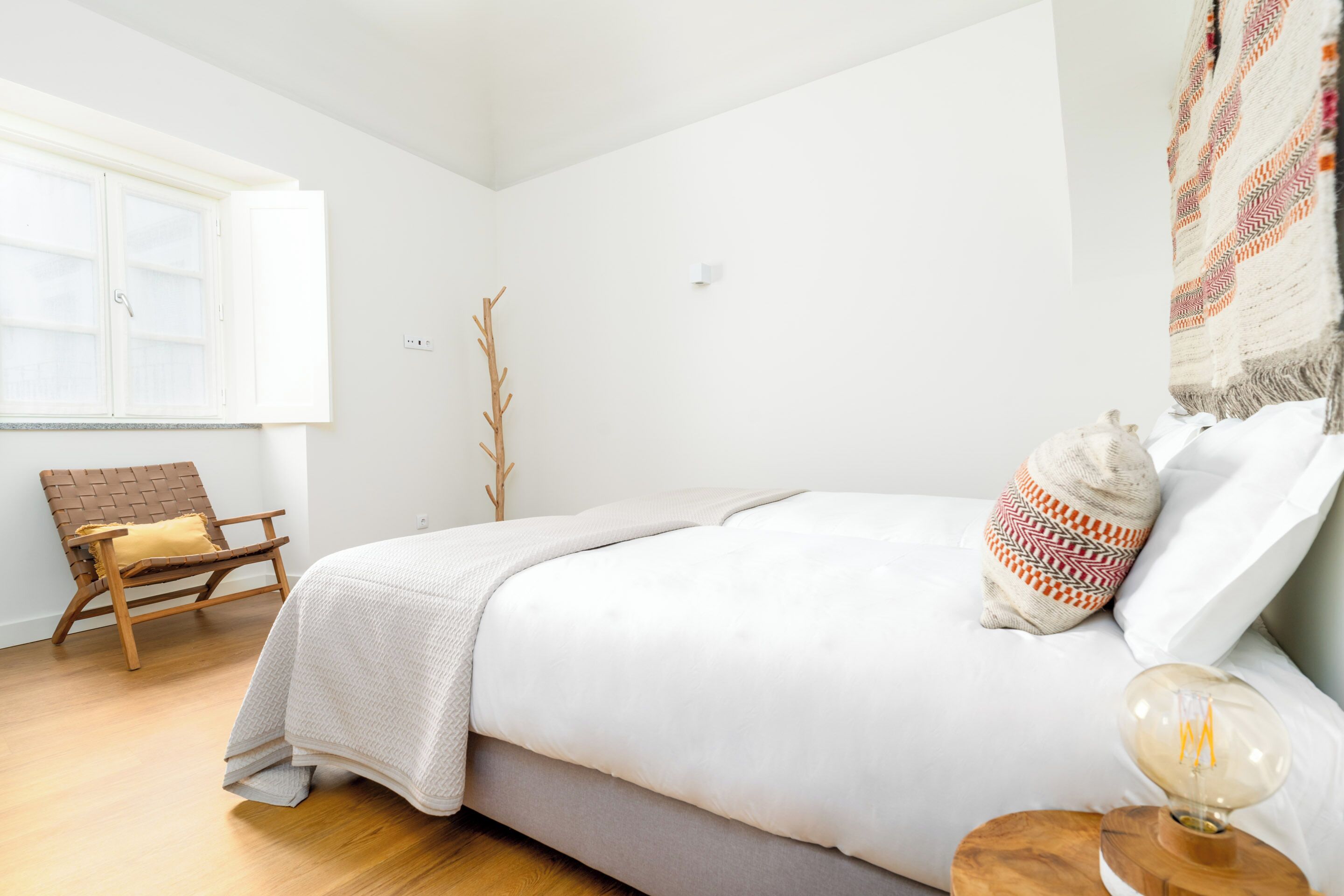 A bedroom with a bed, a chair, a lamp, and a window.